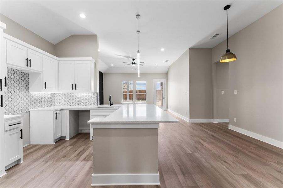 Kitchen featuring tasteful backsplash, pendant lighting, and white cabinets