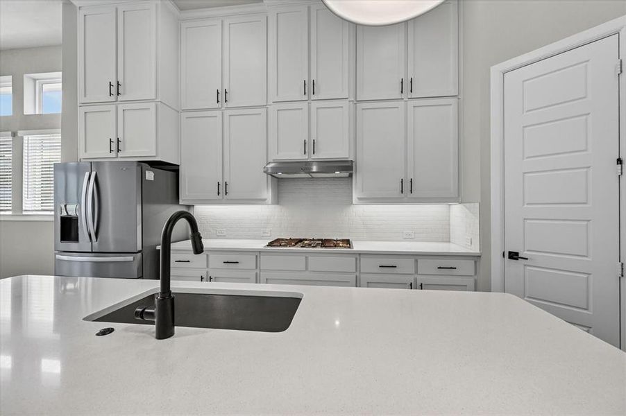 Kitchen featuring white shaker cabinetry, stainless steel appliances, a gas cooktop, and a white subway tile backsplash Kitchen featuring white shaker cabinetry, stainless steel appliances, a gas cooktop, and a white subway tile backsplash