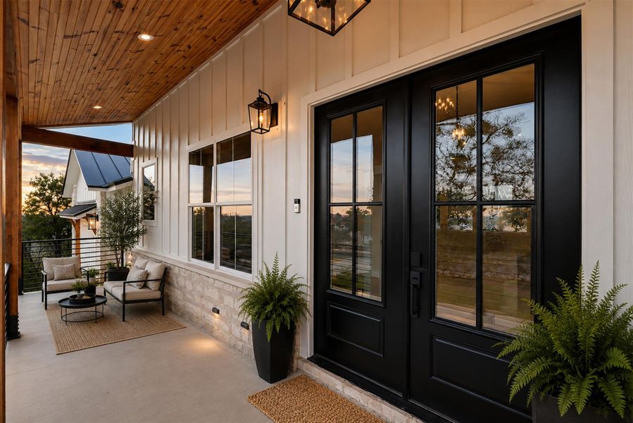 Striking glass-paneled double doors open to a welcoming front porch with warm wood plank ceilings. Striking glass-paneled double doors open to a welcoming front porch with warm wood plank ceilings.