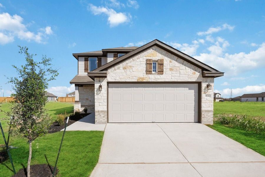 Two-story home with light stone exterior, two-car garage, and concrete driveway