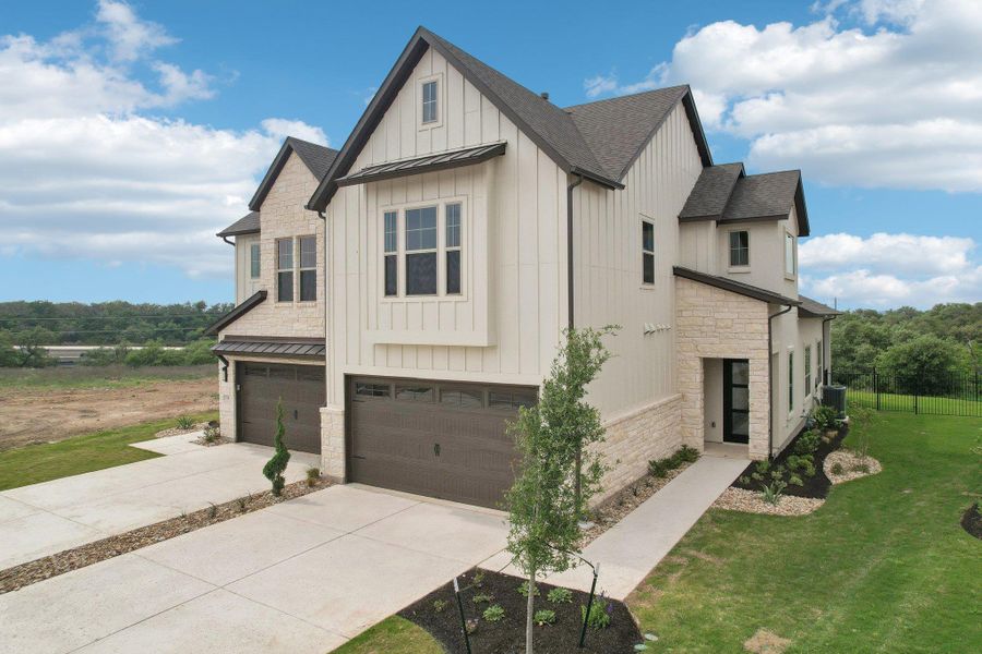 View of side of property featuring a garage, board and batten siding, a standing seam roof, stone siding, and metal roof