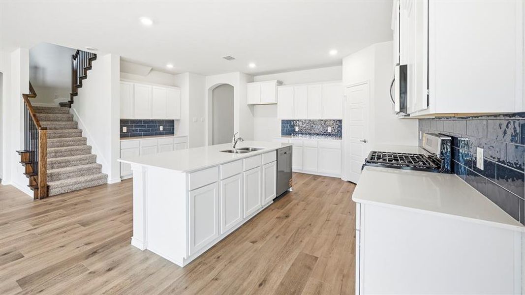 Kitchen featuring white cabinetry, backsplash, stainless steel appliances, a kitchen island with sink, and recessed lighting