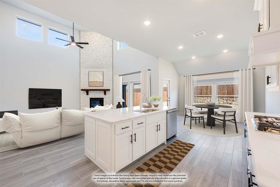 Open-concept kitchen with white island, vaulted ceiling, stone fireplace, and dining area with large windows Open-concept kitchen with white island, vaulted ceiling, stone fireplace, and dining area with large windows