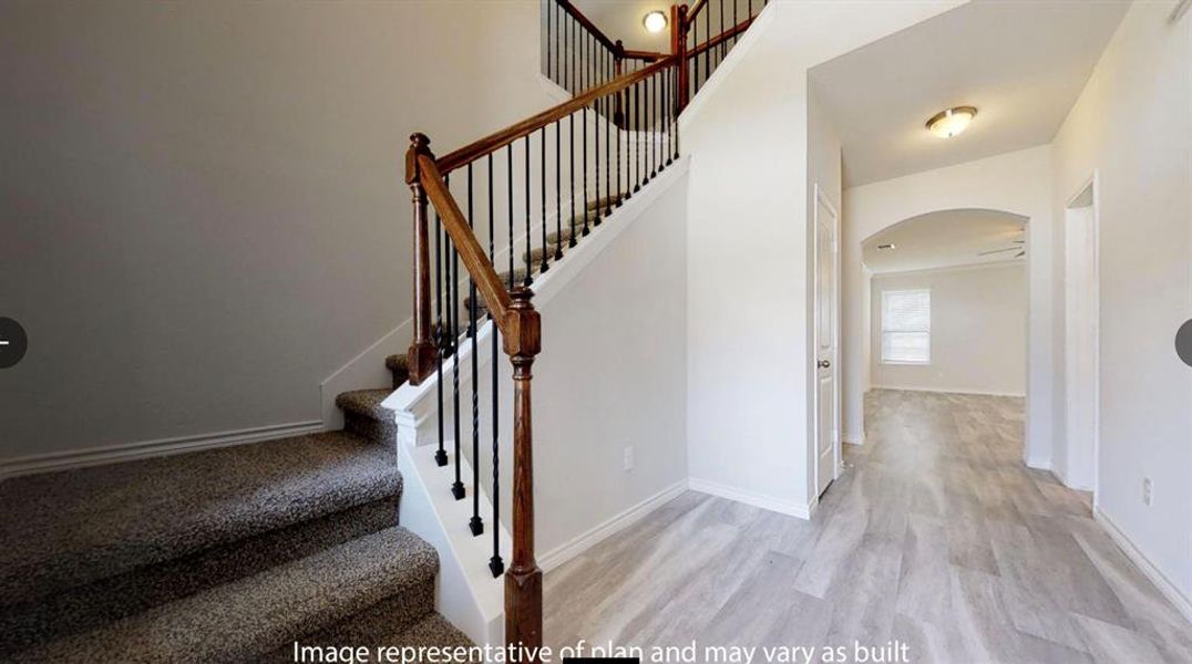 Stairway featuring arched walkways, wood finished floors, and baseboards
