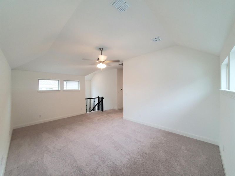 Unfurnished room with light colored carpet, visible vents, a ceiling fan, and vaulted ceiling Unfurnished room with light colored carpet, visible vents, a ceiling fan, and vaulted ceiling