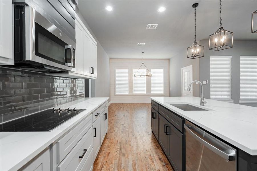 Kitchen with a sink, light wood finished floors, stainless steel appliances, white cabinetry, and visible vents Kitchen with a sink, light wood finished floors, stainless steel appliances, white cabinetry, and visible vents