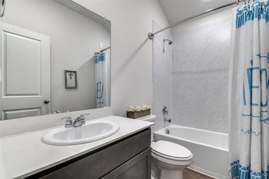 Full bathroom with shower / bath combination with curtain, vanity, toilet, and wood finished floors