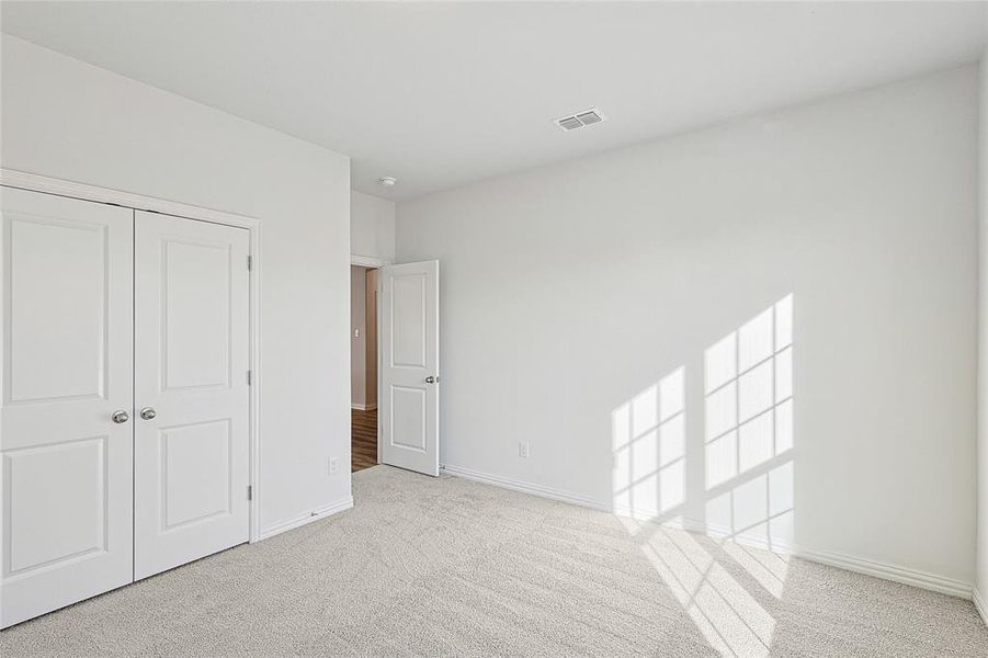 Unfurnished bedroom with light carpet and a closet