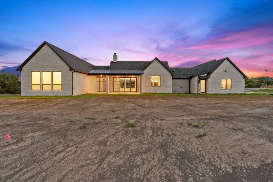 Single-story residence featuring a light-colored brick exterior, dark-toned gabled roofing, and multiple large windows