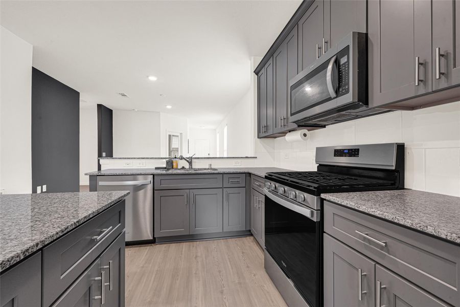 Stylish kitchen view showcasing dark cabinetry, modern countertops, and stainless steel appliances.