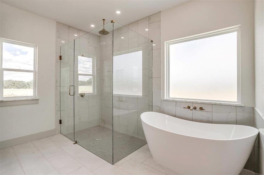 Bathroom featuring plus walk in shower, tile walls, and plenty of natural light