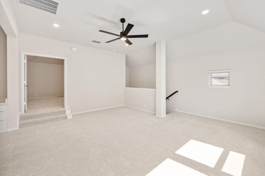 Spacious bonus room with carpet flooring, black ceiling fan, and open staircase landing Spacious bonus room with carpet flooring, black ceiling fan, and open staircase landing