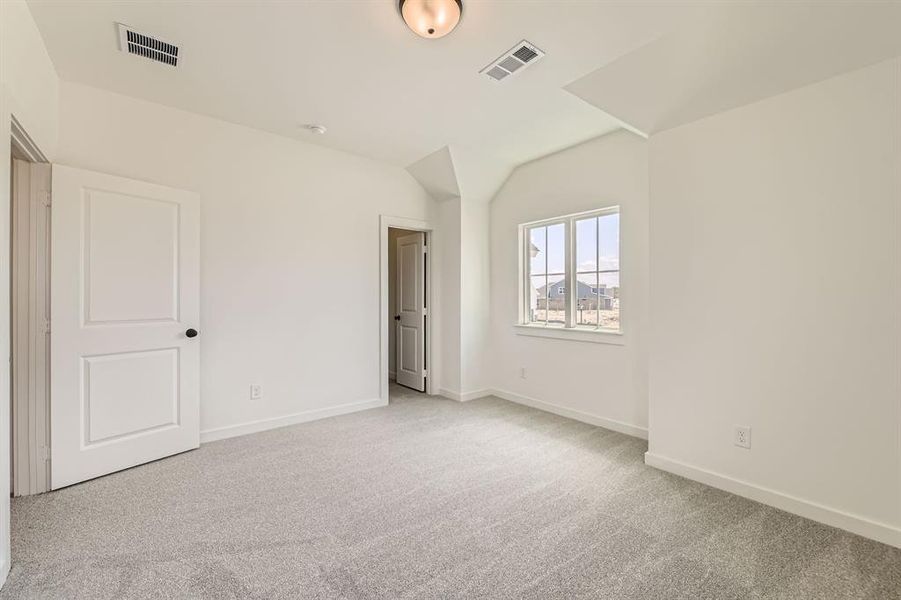 Unfurnished bedroom featuring light carpet, vaulted ceiling, and baseboards Unfurnished bedroom featuring light carpet, vaulted ceiling, and baseboards