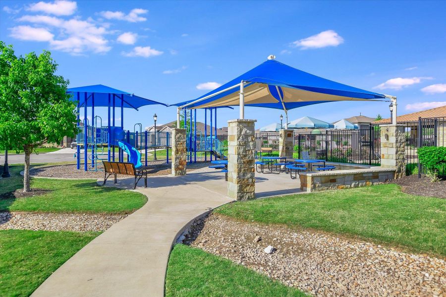 Community playground featuring fence and a lawn