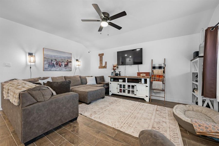 Living room featuring a ceiling fan, vaulted ceiling, and wood finish floors Living room featuring a ceiling fan, vaulted ceiling, and wood finish floors