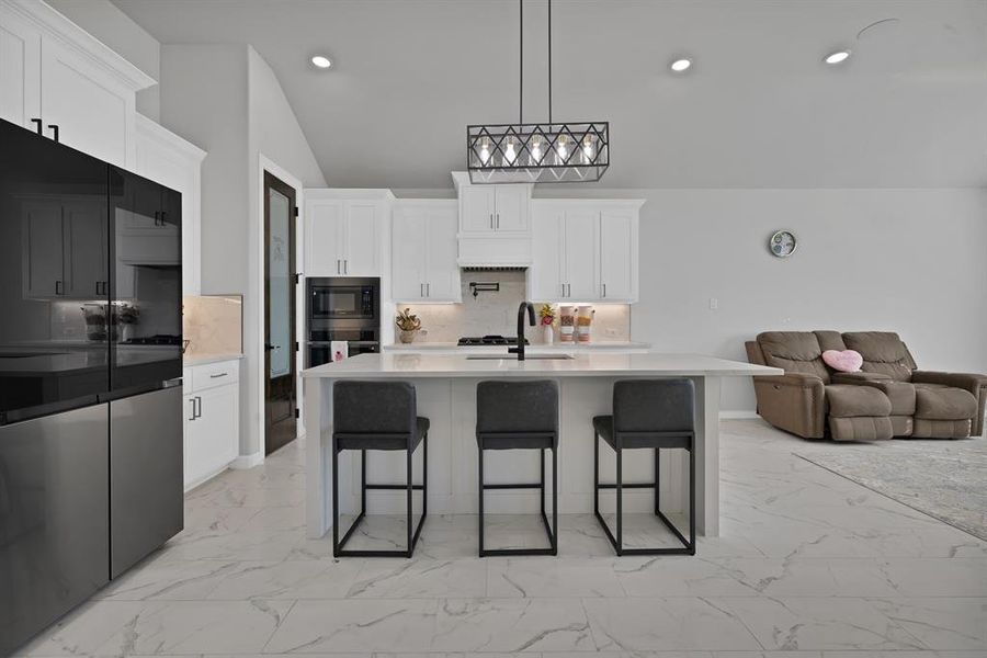 Kitchen with stainless steel oven, marble look floor tile, built in microwave, and open floor plan