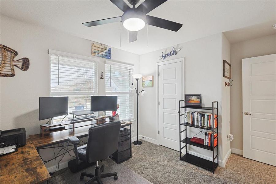 Carpeted office space with ceiling fan and baseboards