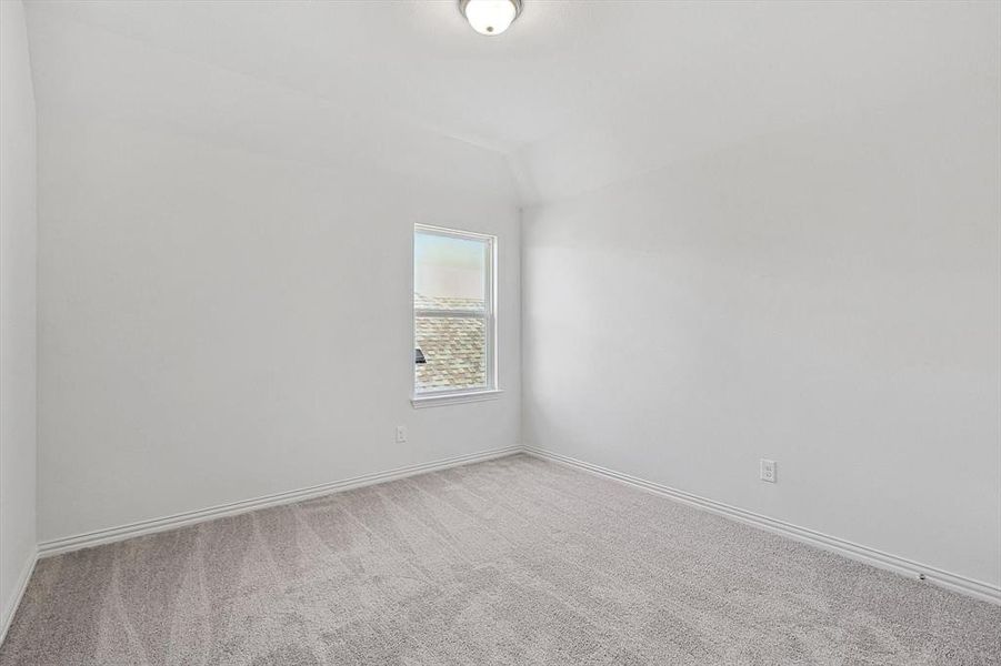 Carpeted empty room featuring vaulted ceiling