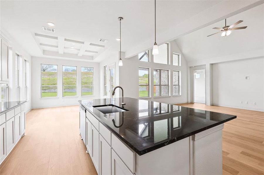 Kitchen featuring coffered ceiling, light hardwood / wood-style floors, a kitchen island with sink, white cabinetry, and sink