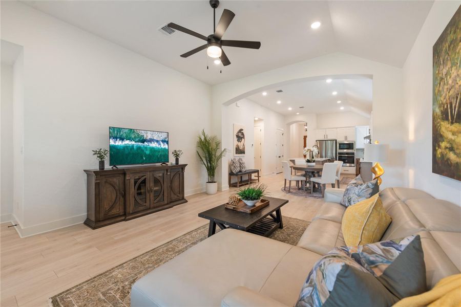An inviting open-concept living area with vaulted ceilings seamlessly connects to the dining and kitchen spaces. An inviting open-concept living area with vaulted ceilings seamlessly connects to the dining and kitchen spaces.