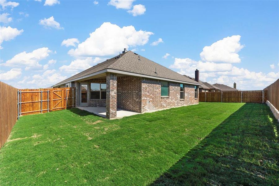 Rear view of property featuring a lawn and a patio area