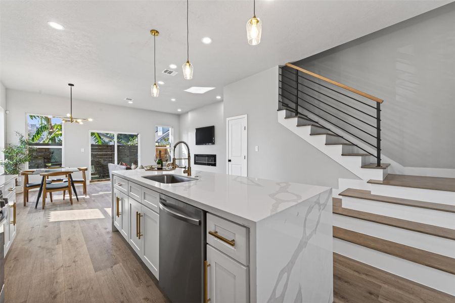 Oversized quartz waterfall island blending style and function paired with designer pendants.