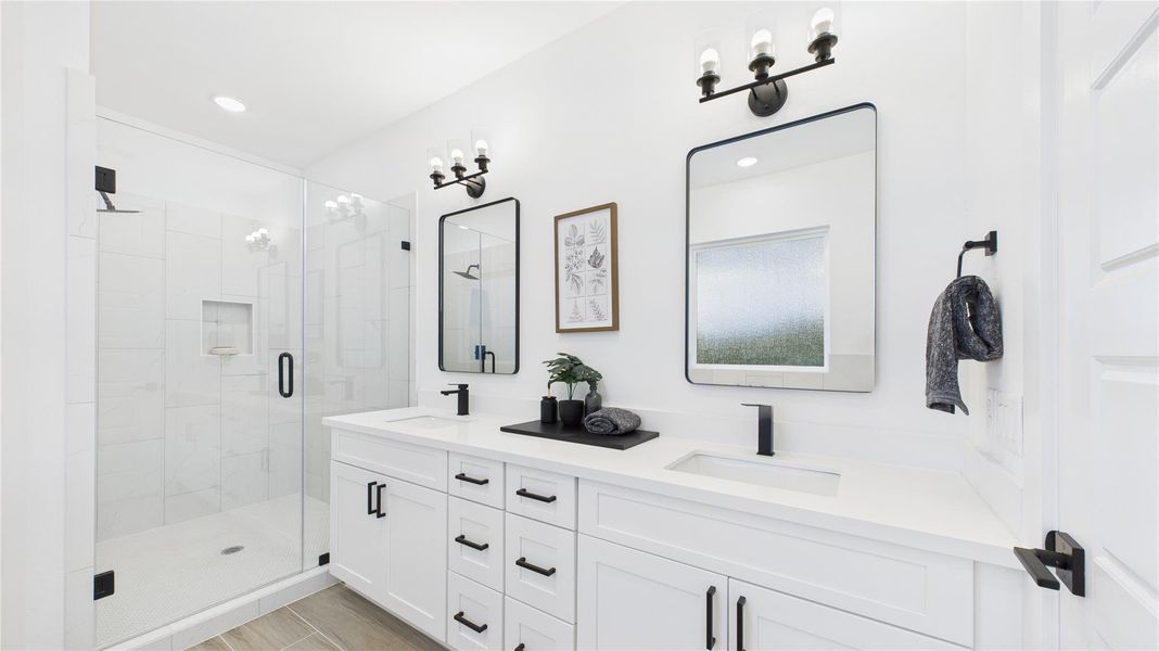 This stylish primary bathroom showcases a spacious walk-in shower framed with sleek glass panels and modern tilework that adds texture and sophistication. A double sink vanity anchors the space with clean lines and ample countertop room, complemented by an abundance of cabinetry that offers both function and flair. Contemporary finishes tie the room together, creating a polished retreat that balances luxury with everyday practicality.