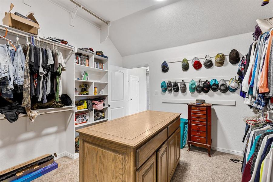 Walk in closet with light carpet and vaulted ceiling