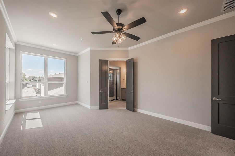 Spacious carpeted room featuring a large window, dark wood-finish doors, recessed lighting, and a ceiling fan with light fixture