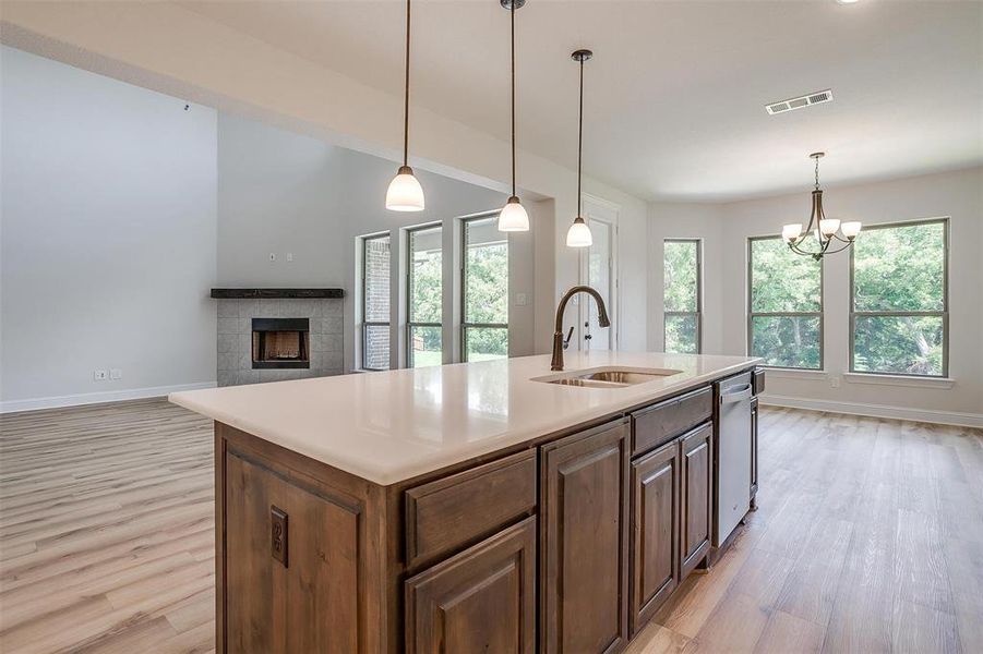 Kitchen with a fireplace, sink, light wood-type flooring, and pendant lighting