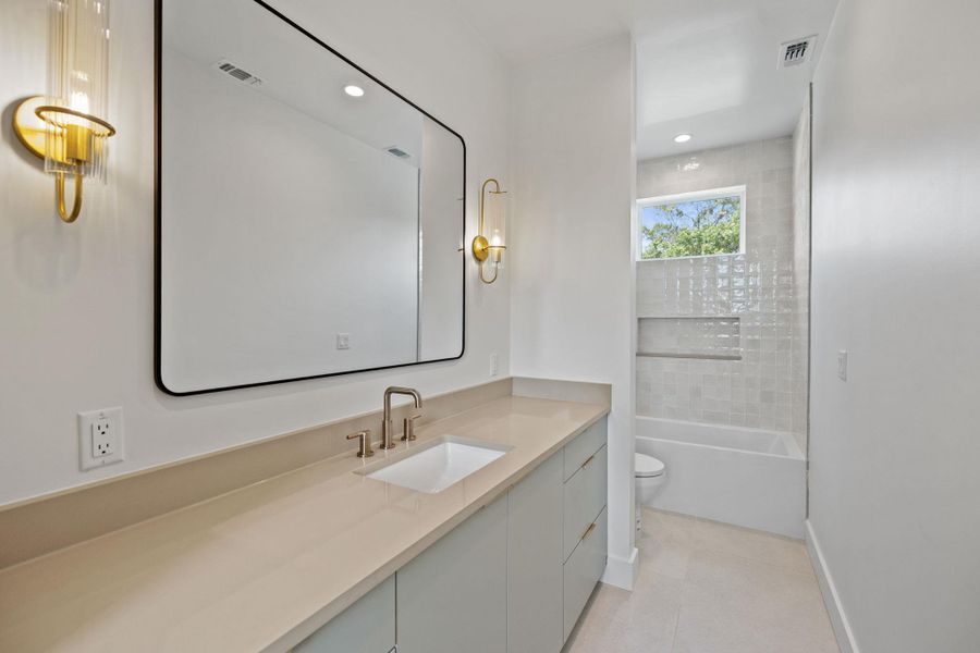 Bathroom with vanity, bathtub / shower combination, light tile patterned floors, and recessed lighting Bathroom with vanity, bathtub / shower combination, light tile patterned floors, and recessed lighting