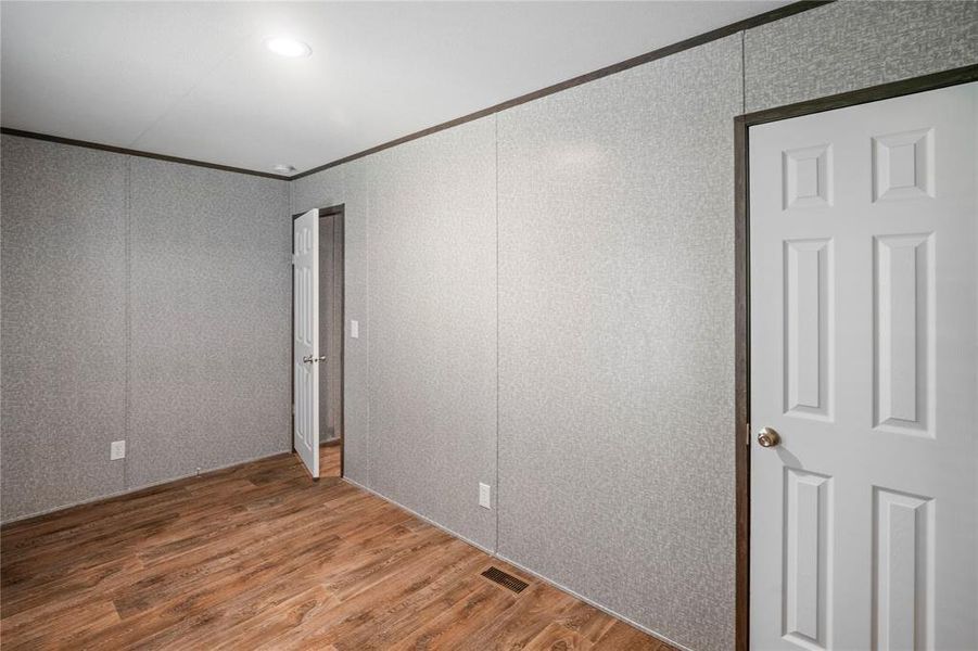 Unfurnished room with crown molding, wood finished floors, and a decorative wall