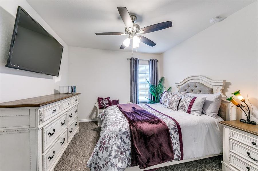 Carpeted bedroom featuring ceiling fan