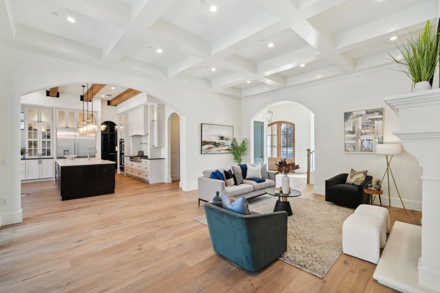 Living room featuring beamed ceiling, light wood-style flooring, recessed lighting, arched walkways, and baseboards