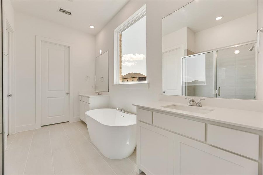 Full bath with a soaking tub, two vanities, a stall shower, light tile patterned floors, and recessed lighting Full bath with a soaking tub, two vanities, a stall shower, light tile patterned floors, and recessed lighting