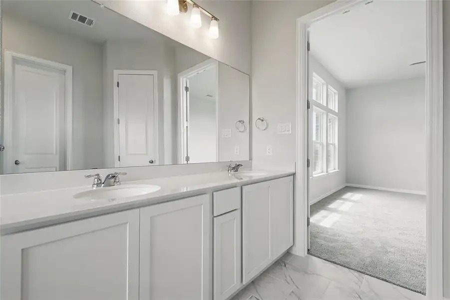 Full bathroom featuring double vanity, marble look tiles, and baseboards