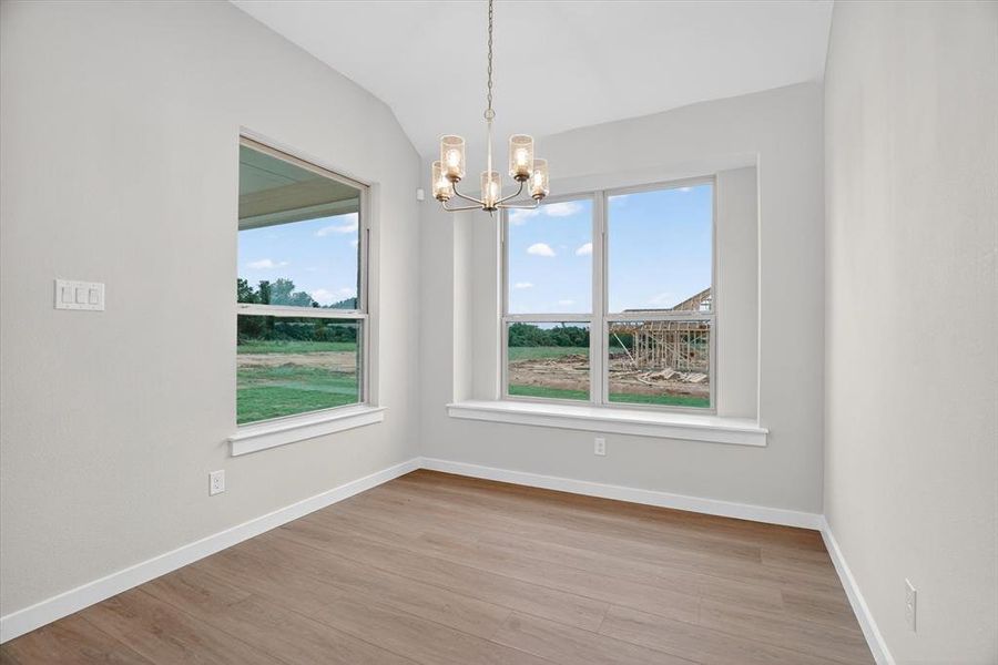 Bright interior room featuring wood-finish flooring, white baseboards, and light neutral wall paint