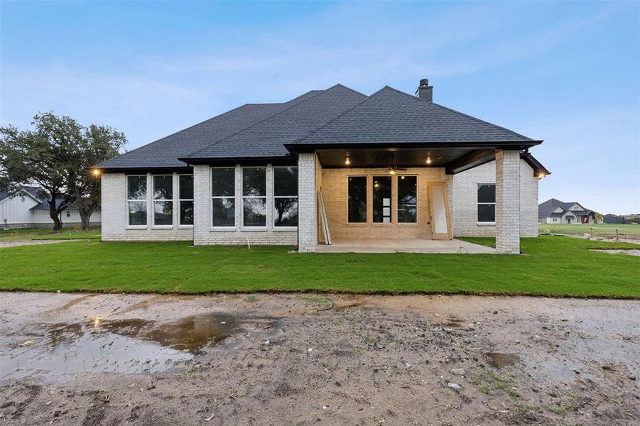 Rear view of house with a lawn and a patio