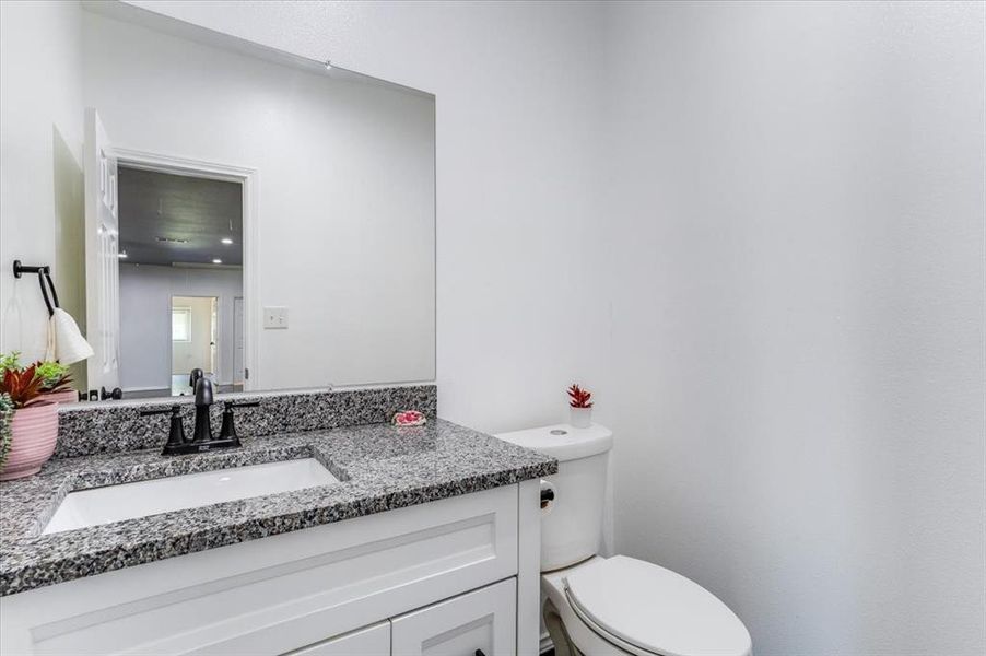 Bathroom featuring a white vanity with shaker-style cabinetry, a granite countertop, an undermount sink, and a black faucet