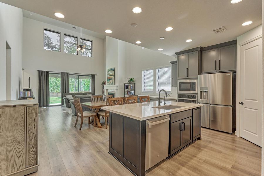 Discover the perfect blend of style and space in this inviting open concept living area, featuring a sleek kitchen island, modern appliances, and seamless flow into a bright, airy dining and living space with high ceilings and abundant natural light.