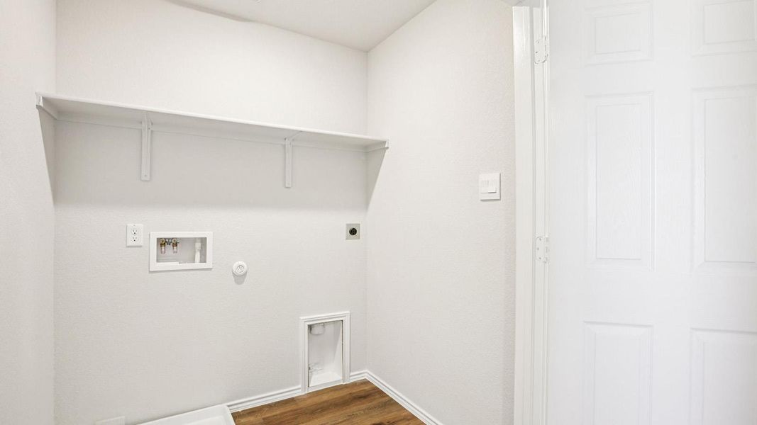 Dedicated laundry area featuring a utility hookup box, dryer vent, and wood-finish flooring