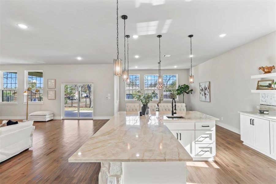 Kitchen with a center island with sink, open floor plan, light stone counters, decorative light fixtures, and recessed lighting Kitchen with a center island with sink, open floor plan, light stone counters, decorative light fixtures, and recessed lighting