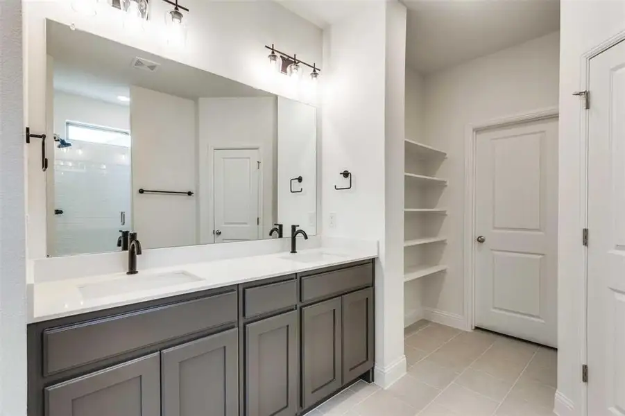 Full bathroom with double vanity, a shower stall, and tile patterned floors