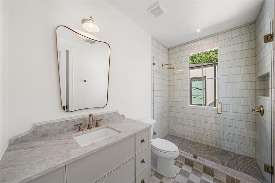 Contemporary bathroom featuring a vanity with an integrated sink and stone countertop, a wall-mounted mirror, and a walk-in shower with a glass enclosure and window