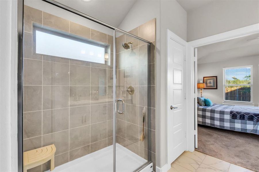 Bathroom with a shower with shower door and lofted ceiling