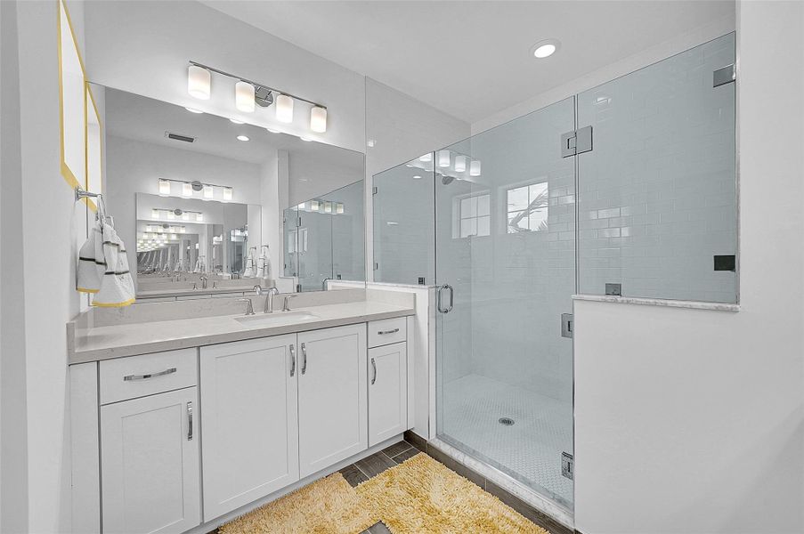 Primary bathroom has large shower with glass enclosure with  Upscale lighting.