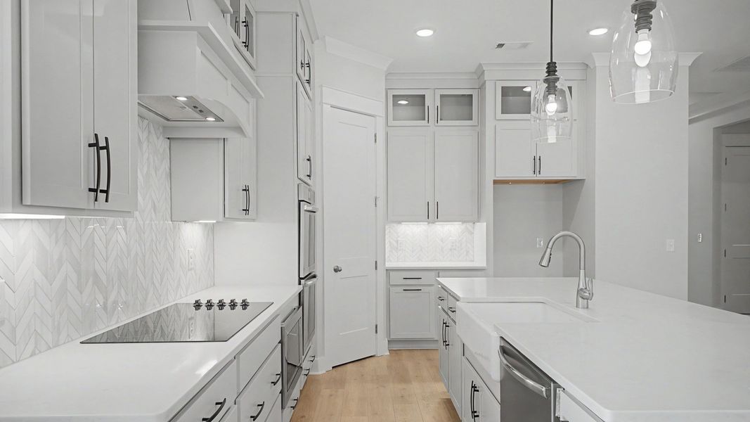 Kitchen with floor to ceiling cabinets, quartz countertops, tile backsplash, and vent hood