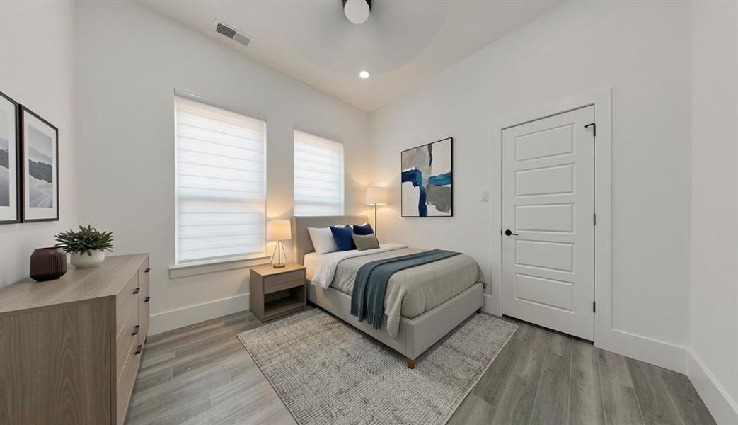 Bedroom featuring wood-finish flooring, two large windows with blinds, a five-panel interior door with matte black hardware, recessed lighting, and a ceiling fan Bedroom featuring wood-finish flooring, two large windows with blinds, a five-panel interior door with matte black hardware, recessed lighting, and a ceiling fan
