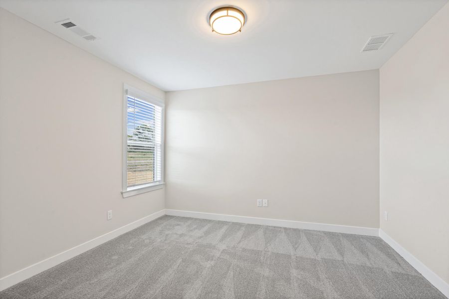 Neutral-toned room featuring a single window with horizontal blinds, light gray wall-to-wall carpeting, white baseboards, and a flush-mount ceiling light fixture Neutral-toned room featuring a single window with horizontal blinds, light gray wall-to-wall carpeting, white baseboards, and a flush-mount ceiling light fixture