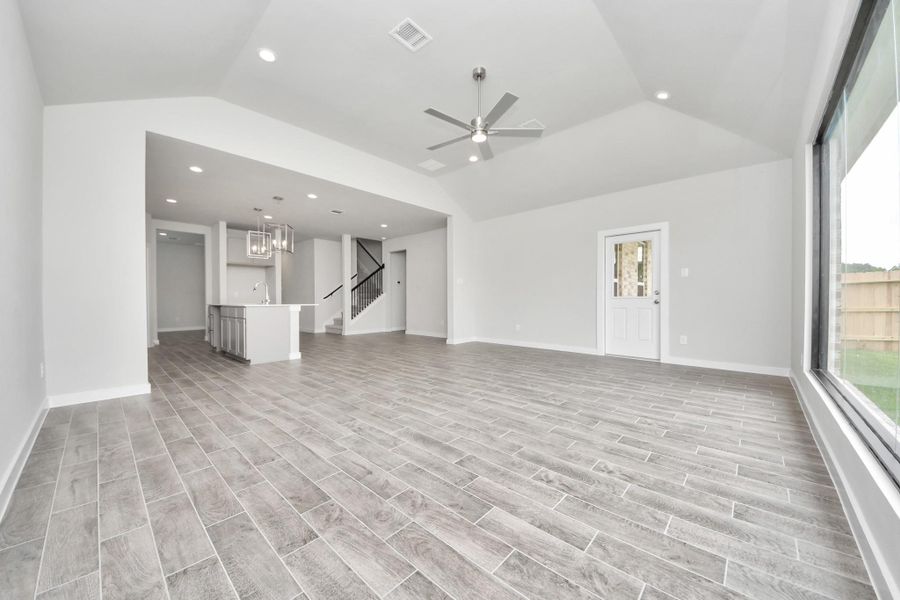 Relax and unwind in this inviting family room, illuminated by abundant natural light streaming in through tall windows, complemented by high ceilings and stunning flooring. Stay comfortable year-round with the gentle breeze from the ceiling fan, creating the perfect atmosphere for family gatherings. Sample photo of completed home with similar floor plan. Actual colors and selections may vary.